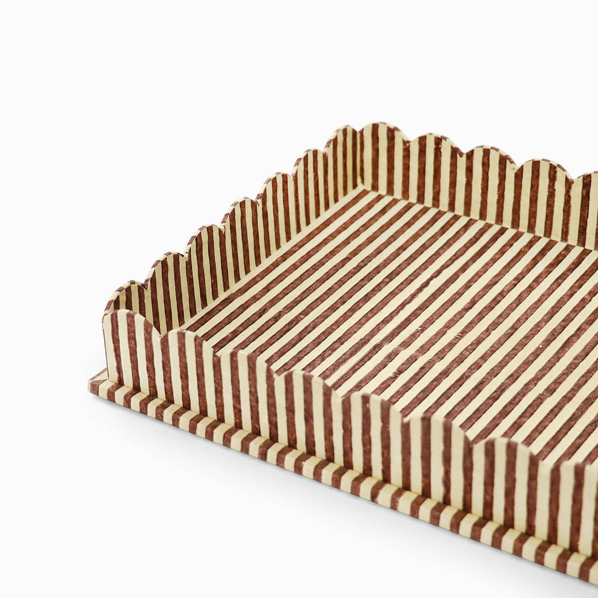 Close view of scalloped serving tray edge and striped block print in brown and cream