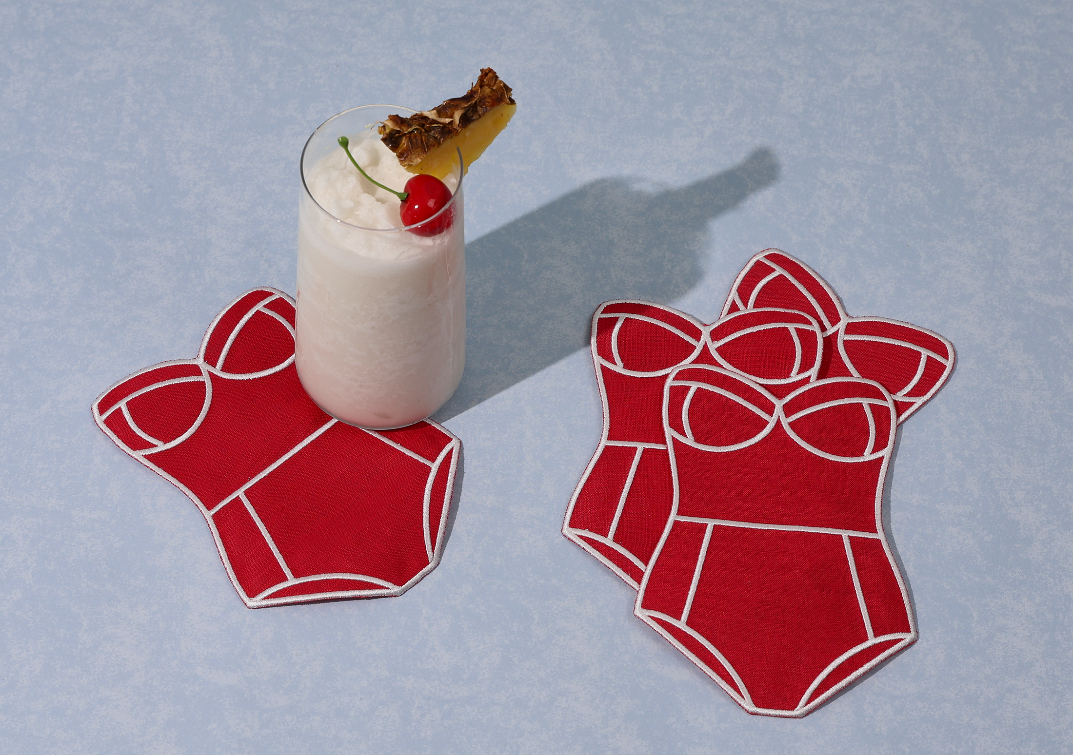 Set of red swimsuit-shaped cocktail napkins with white piping and bust straps