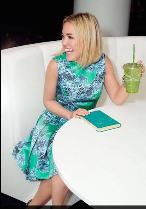 Gift card in hand on table, with teal patterned dress sleeve